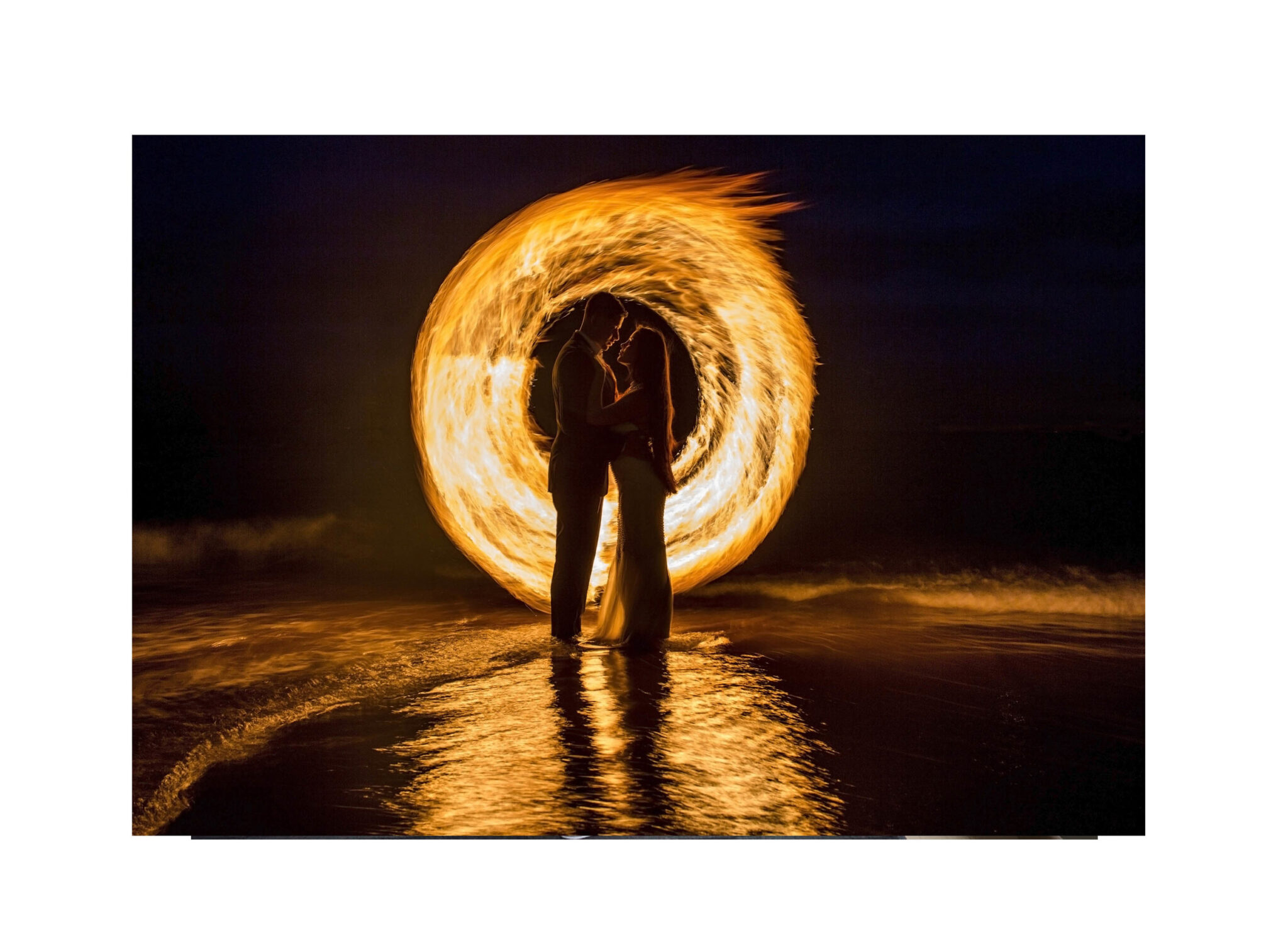 Couple embracing inside a glowing ring of fire on a beach at night