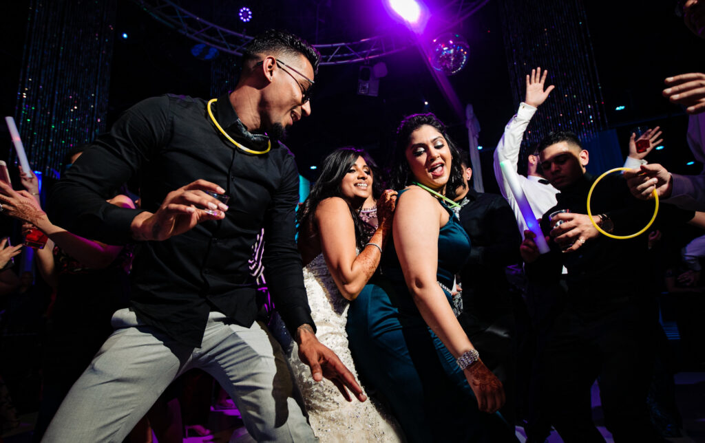 Guests dancing at an event under purple and blue lights