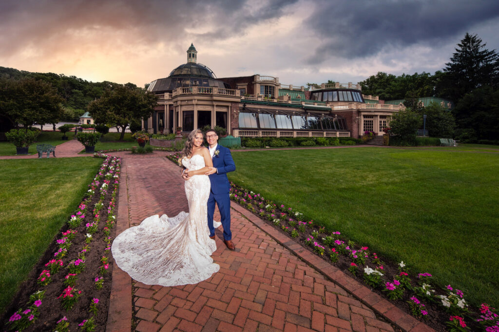 Couple on a garden path in front of a grand building at sunset
