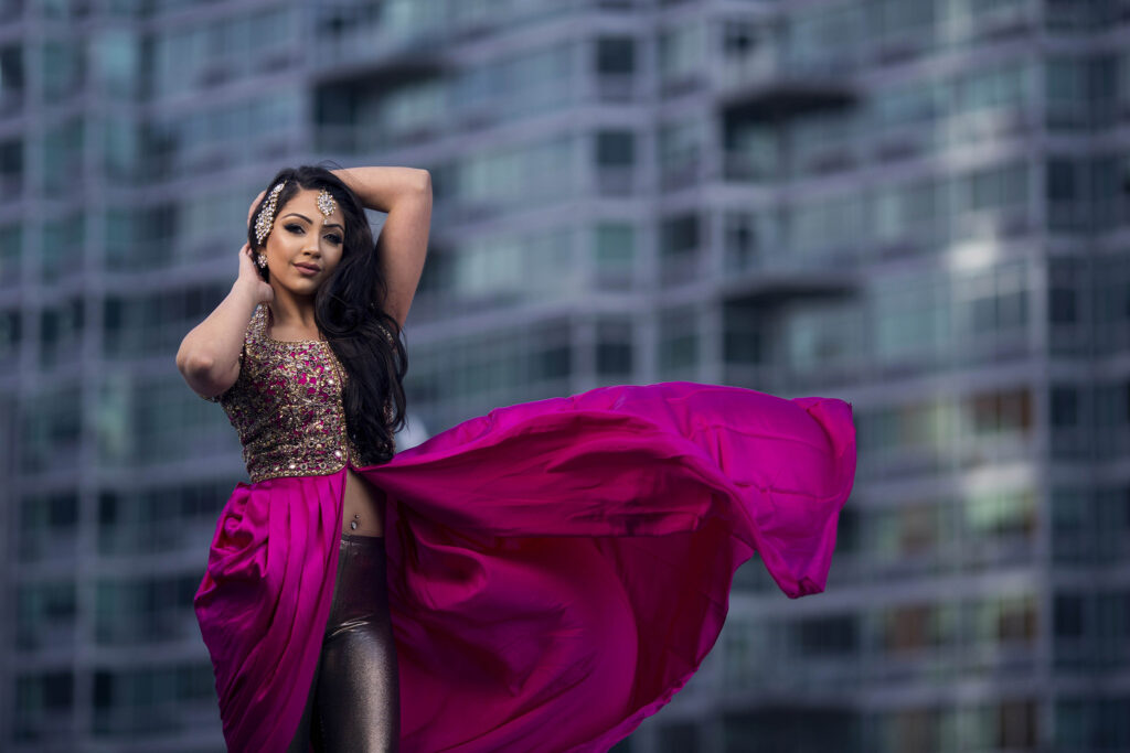 Woman in a flowing pink skirt posed against a city backdrop